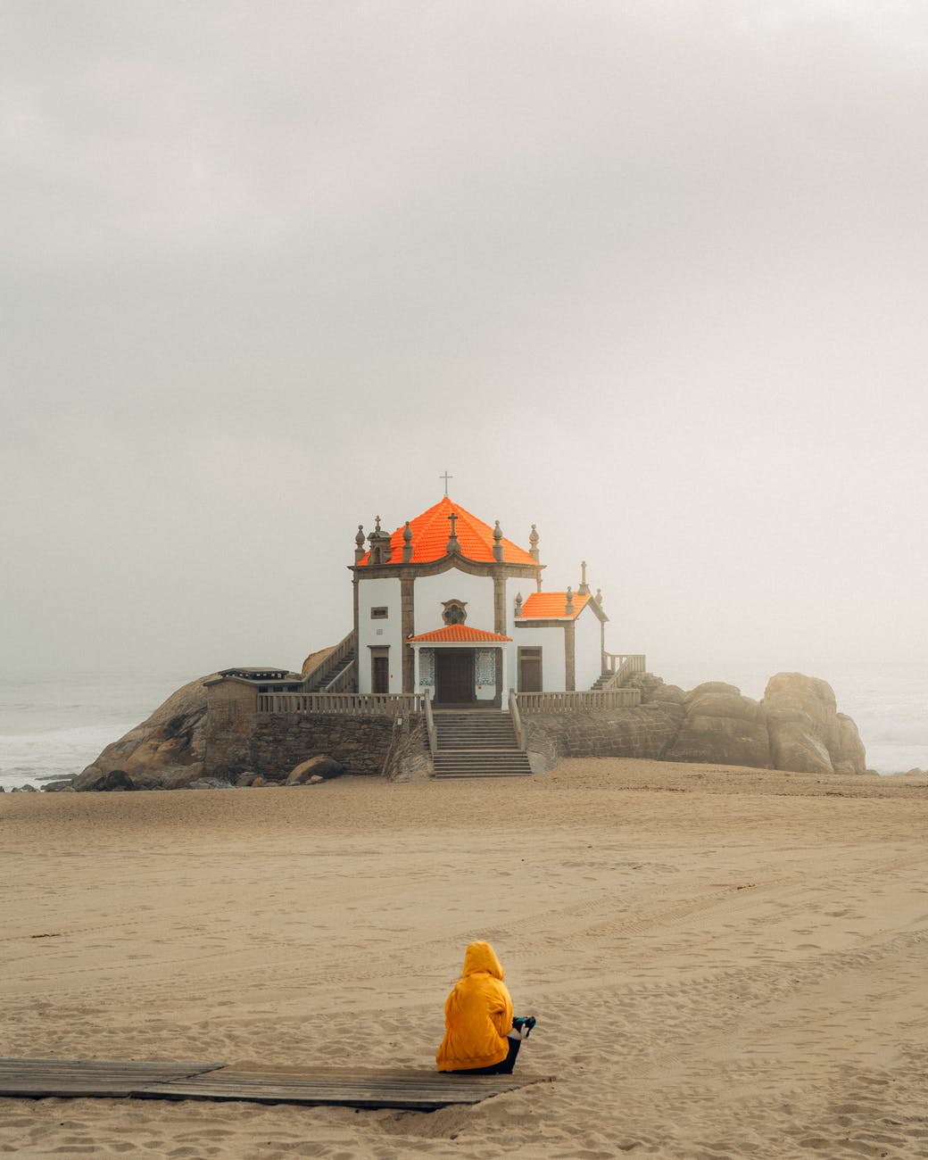 person sitting on seashore overlooking cathedral