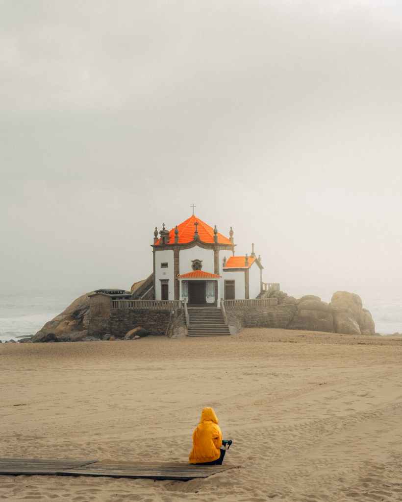 person sitting on seashore overlooking cathedral